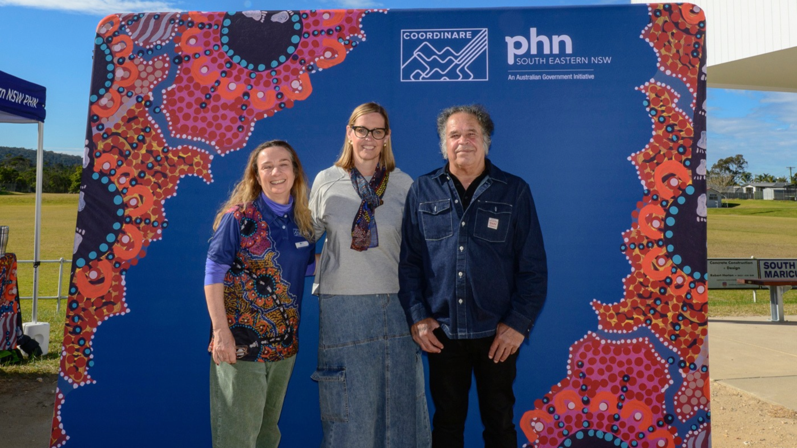 hree people standing together in front of a COORDINARE South Eastern NSW PHN backdrop at the Health Check Convoy in Eden.
